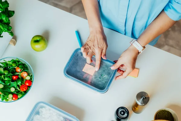 Kilo vermek için sağlıklı bir diyet planı, günlük hazır yemek menüsü. Yakından bir kadın beslenme çantasına önceden pişirilmiş, akşam yemeği için hazır bir not bırakıyor. Sağlıklı yemekle dengeli porsiyon. Pişirme öncesi konsept.
