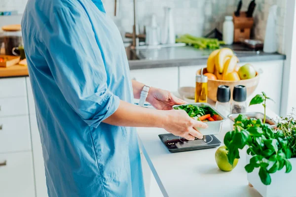 Healthy diet plan for weight loss, daily ready meal menu. Close up Woman weighing lunch box cooked in advance,ready to eat on kitchen scale. Balanced portion with healthy dish. Pre-cooking concept. — Stock Photo, Image