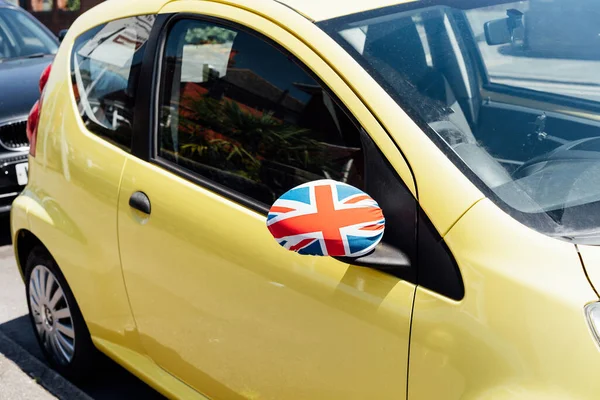 Union Jack flag on the private car side door mirror is coated with textil decor. Great Britain national flag colors. Festive Car Decor for Queen jubilee celebration. Patriotic concept