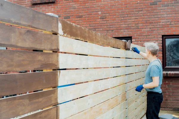 Young Man Worker Paints Roller Wooden Board Fence Garden Diy — Stock Photo, Image