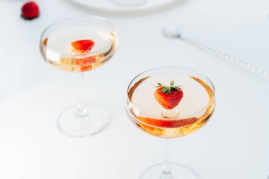 Kokteyl bardaklarında kokteyl içecekler ve beyaz masada taze çilek. Yaz partisi için hafif bir içki. Seçici odak, boşluğu kopyala