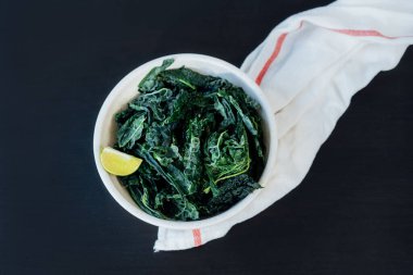Üst manzara tabakta yeşil kıvırcık lahana yaprakları, baharatlar ve mutfak masasında zeytinyağı. Lahana cipsi ya da sağlıklı salata yemeği için malzemeler. Sağlıklı beslenme, beslenme. Seçici odak