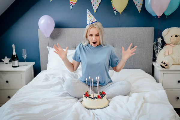 Happy Woman Pajama Party Cap Blowing Out Candles Birthday Cake — Stockfoto