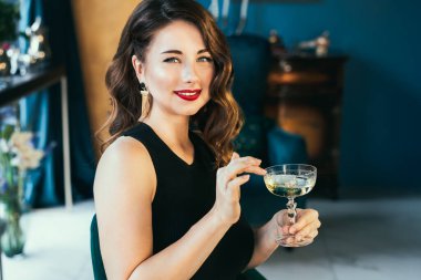 Portrait of posh elegant woman in evening dress with a glass of champagne in the luxury interior. Celebrity, superstar lifestyle. Party, drinks, holidays and celebration concept. Selective focus.