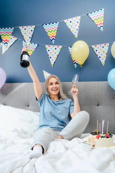 Happy Emotional Woman Pajama Party Cap Sitting Bed Festive Cake — стоковое фото