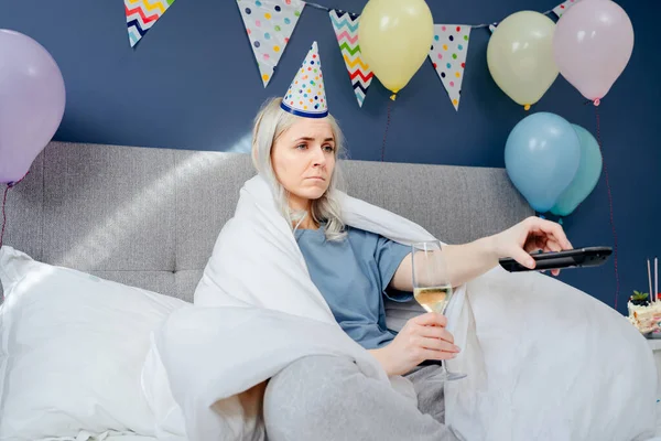 Sad Woman Pajamas Party Cap Drinks Champagne Watches Wrapped Blanket — Stockfoto