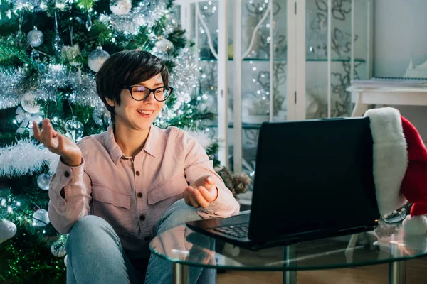 Woman having online video chat and talking to her friends or family on virtual call. Christmas online celebration. Happy New Year online party. Video conference chat on laptop. Selective focus.