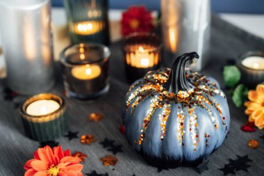 Autumn cozy mood composition for home decoration. Gray pumpkin with sequins, burning candles and fresh dahlia flowers on the tray with napkin. Fall, hygge home decor. Selective focus. Copy space