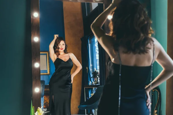 칵테일 드레스를 럭셔리 실내에서 거울에 변덕스럽고 감넘치는 아가씨 슈퍼스타의 선택적 — 스톡 사진