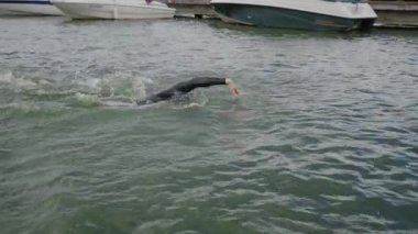 Profesyonel yüzücü, dalgıç kıyafetli triatloncu açık denizde yüzer, profesyonel bir sporcu triatlon yarışmasından önce antrenman yapar, 4k süper yavaş çekim.
