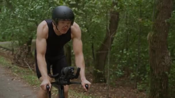 Super slow motion, Triathlète fait du vélo, cycliste pro sur une route forestière, préparation aux compétitions et entraînement d'endurance, vue de face. — Video