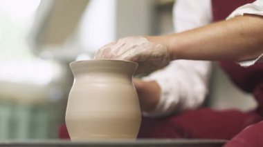 Çamur masa takımı üretimi, çömlekçi çamurdan bir sürahi yapar, ellerin yakın görüntüsü, el işi, çömlek atölyesi.