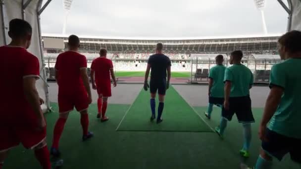 Jugadores de fútbol profesional camina hacia el estadio, equipos de fútbol rivales caminan a través del estadio, vista trasera, partido de fútbol. — Vídeos de Stock