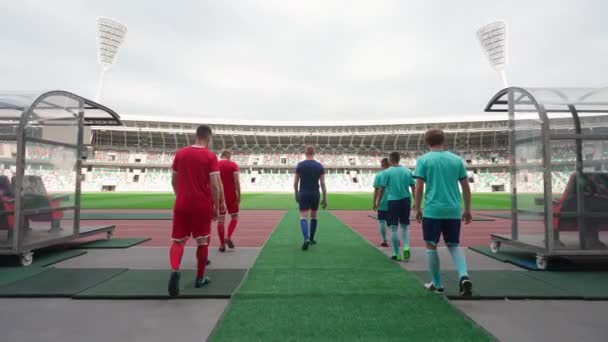Professionele voetballers lopen naar het stadion, rivaliserende voetbalteams lopen door het stadion, achteraanzicht, 4k slow motion. — Stockvideo