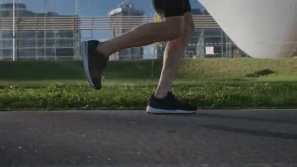 Morning jog,o runner run on a city road, athlete trains in an urban environment on a sunny day, modern urban landscape, preparation for triathlon competitions, low angle view. — Stock Video