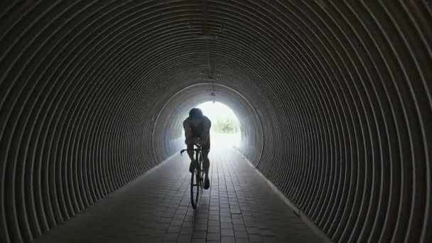 प्रो ट्रायथलेट एक कटिंग बाइक पर सवारी करता है, एक सुरंग में समर्थक साइकिल चालक सवारी करता है, दौड़ के लिए एथलीट प्रशिक्षण, 4k धीमी गति . — स्टॉक वीडियो