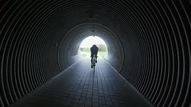 Triatleta monta uma bicicleta de corte, passeios de ciclista pro em um túnel, treinamento de atleta para corrida, 4k câmera lenta. — Vídeo de Stock