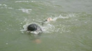 Profesyonel yüzücü, dalgıç kıyafetli triatloncu açık denizde yüzer, triatlon yarışmasından önce antrenman yapan bir sporcu, 4 km yavaş çekim..