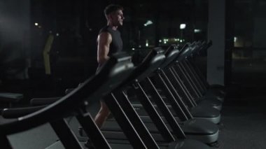 Atletik koşucu, koşu bandında koşan bir adam, spor salonunda aerobik egzersiz ve dayanıklılık eğitimi, gece antrenmanında motivasyon, 4k ağır çekim..