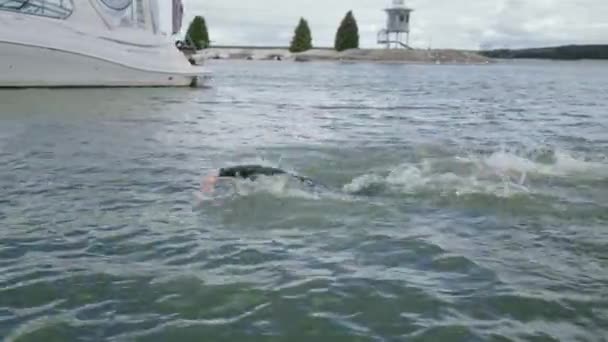 Профессиональный пловец, триатлонист в гидрокостюме плавает в открытой воде, спортсмен тренируется перед соревнованиями по триатлону. — стоковое видео