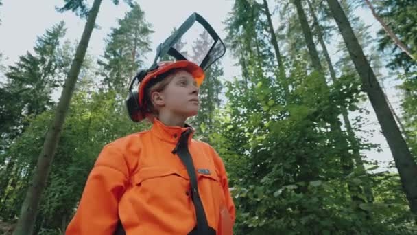 Retrato de uma madeireira em pé na floresta, uma jovem especialista em equipamentos de proteção, 4k câmera lenta. — Vídeo de Stock