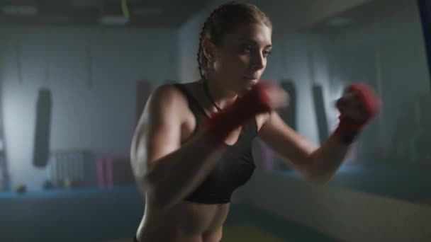 Žena bojovník porazí boxovací pytel a trénuje jeho údery,, tréninkový den v boxerské tělocvičně, samice udeří rychle, 4k zpomalený film. — Stock video