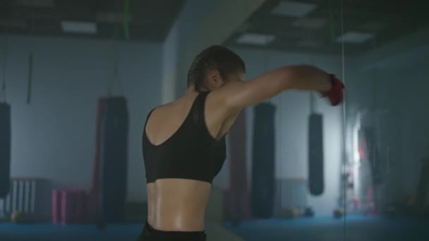 Woman fighter trains his punches and defense in the boxing gym, a boxer trains in front of a mirror, fight with reflection, 4k slow motion. — Stock Video