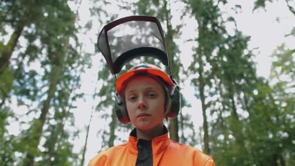 Retrato de uma mulher madeireira em pé na floresta, especialista feminino em equipamentos de proteção olha para a câmera, 4k câmera lenta. — Vídeo de Stock