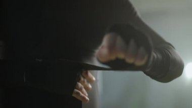 Erkek dövüşçü ellerini boks bandajlarıyla sarar, spor salonunda kickboks antrenmanı yapar, dövüşçü savaşa hazırlanır, 4k ağır çekim..