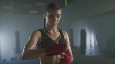 Kadın boksör ellerini boks bandajlarıyla sarar. Spor salonunda boks antrenmanı yapar. Kadın boksör savaşa hazırlanır..