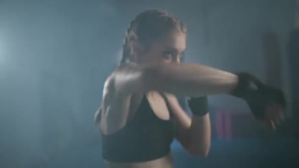 Joven luchadora entrena sus golpes, entrenando en el gimnasio de boxeo, mujer entrena una serie de golpes rápido, vista frontal. — Vídeos de Stock