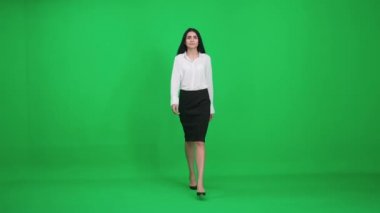 Takım elbiseli bir kadın yeşil arka planda yürür, iş kadını yaklaşır ve kameraya bakar, gülümseyen kadın, kromakey şablonu.