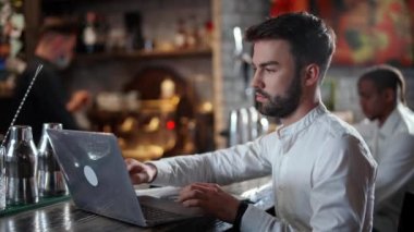 Freelancer evin dışında çalışıyor. Genç bir müteahhit barda oturuyor ve dizüstü bilgisayar kullanıyor..
