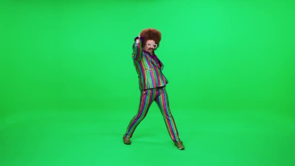 Çok renkli takım elbiseli bir retro adam yeşil arka planda komik bir dans ediyor, neşeli bir ruh hali, eski bir disko adamı yeni yıl partisinde eğleniyor.. — Stok video