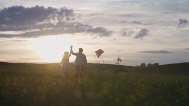 Familie outdoor recreatie, een jongen met zijn ouders rennen door het veld lanceren van een vlieger, een jong gezin in de natuur, zonsondergang tijd, 4k slow motion. — Stockvideo