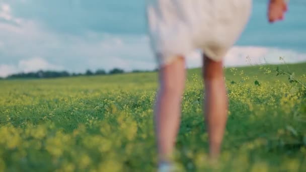 Platteland, jong koppel in de natuur, man en vrouw rennen door een veld van koolzaad hand in hand, slow motion. — Stockvideo
