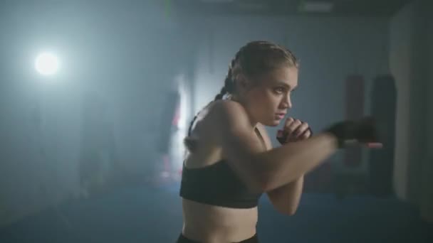 Joven luchadora entrena sus golpes, entrenando en el gimnasio de boxeo, mujer entrena una serie de golpes rápido. — Vídeos de Stock