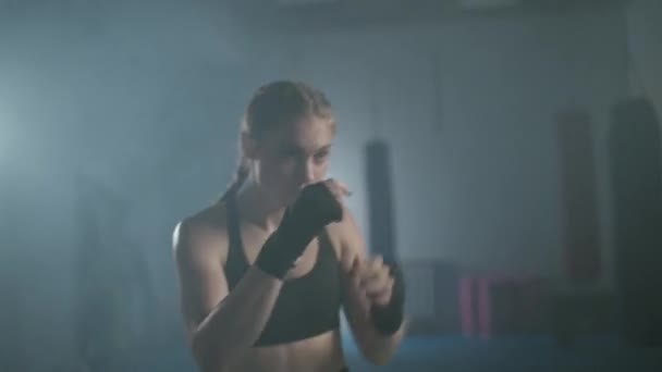 Mulher lutadora treina seus socos, treinando no ginásio de boxe, feminino treina uma série de socos rápido, poder da mulher. — Vídeo de Stock