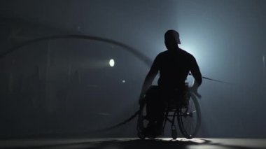 Tekerlekli sandalyedeki engelli adam, savaş halatları, dayanıklılık eğitimi, beden eğitimi ve fiziksel aktivitelerle egzersiz yapıyor..