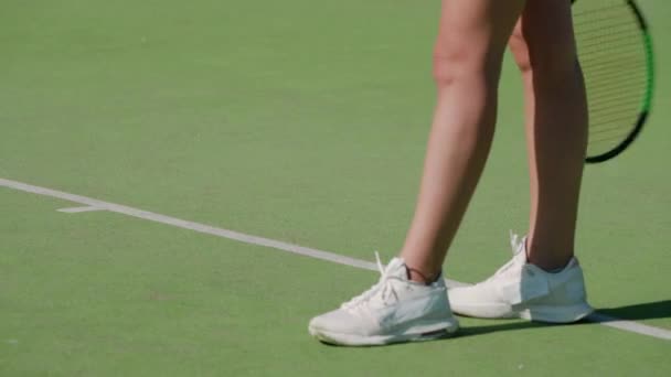 Female tennis player hits a ball off the floor in a outdoor court, view of the legs, training day. — Stock Video