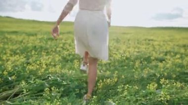 Kırsal kesimde, beyaz elbiseli, kimliği belirsiz genç bir kız tarlada koşuyor, 4k ağır çekim..