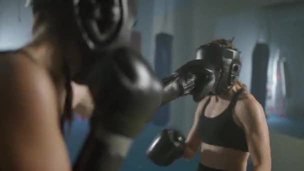 Lutando luta de duas lutadoras usando capacetes protetores, treinamento no ginásio de boxe, mulheres treinam defesa e série de socos em uma batalha. — Vídeo de Stock