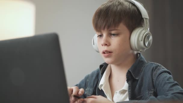 Портативний, дистанційне навчання за допомогою відеокасети, білий підліток сидить на робочому місці у вітальні і використовує ноутбук для навчання в самоізоляції вдома, пише хлопчик в блокноті . — стокове відео