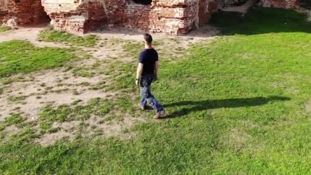 Turismo, hombre caminando por el patio verde cerca del antiguo edificio antiguo, ruinas históricas, descubriendo — Vídeos de Stock