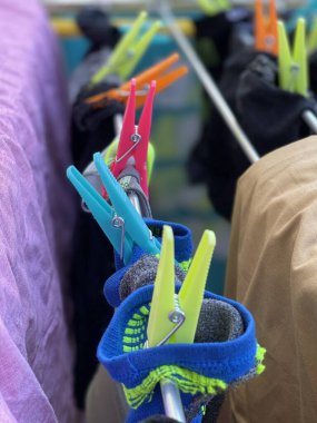 Çamaşır ipinde mandallarla asılı renkli elbiseler.