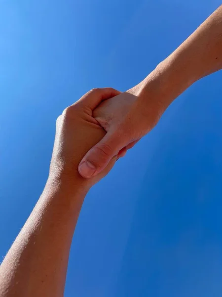 two women holding hands with blue sky background
