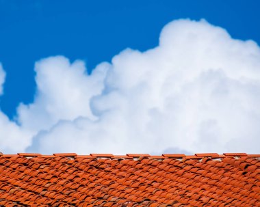 Arka plan olarak beyaz bulutlu kırmızı çatı kiremitleri