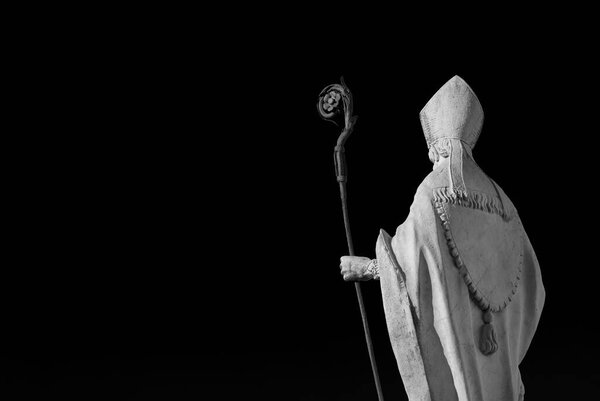 Catholic Church. Bishop with mitre and crosier, an old white marble statue on Lucca old walls, erected in the 17th century (Black and White with copy space)