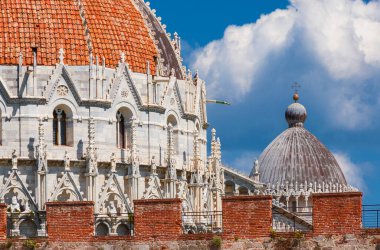 Pisa 'nın ünlü simgeleri: Vaftizcilik ve Katedral ortaçağ kubbeleri, şehrin dışından görülür antik duvarlar, mavi gökyüzü ve beyaz bulutlar