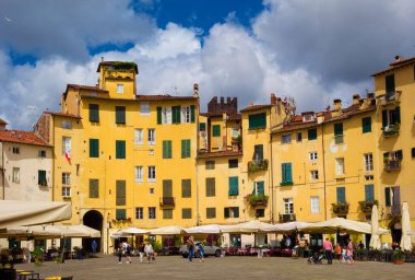 Lucca, ITALY, 14 Temmuz 2021 - Lucca 'nın tarihi merkezinde tarihi Roma harabeleri üzerine inşa edilmiş evler, dükkanlar ve restoranlar ile ünlü Piazza dell' Anfiteatro (Amfitiyatro Meydanı)
